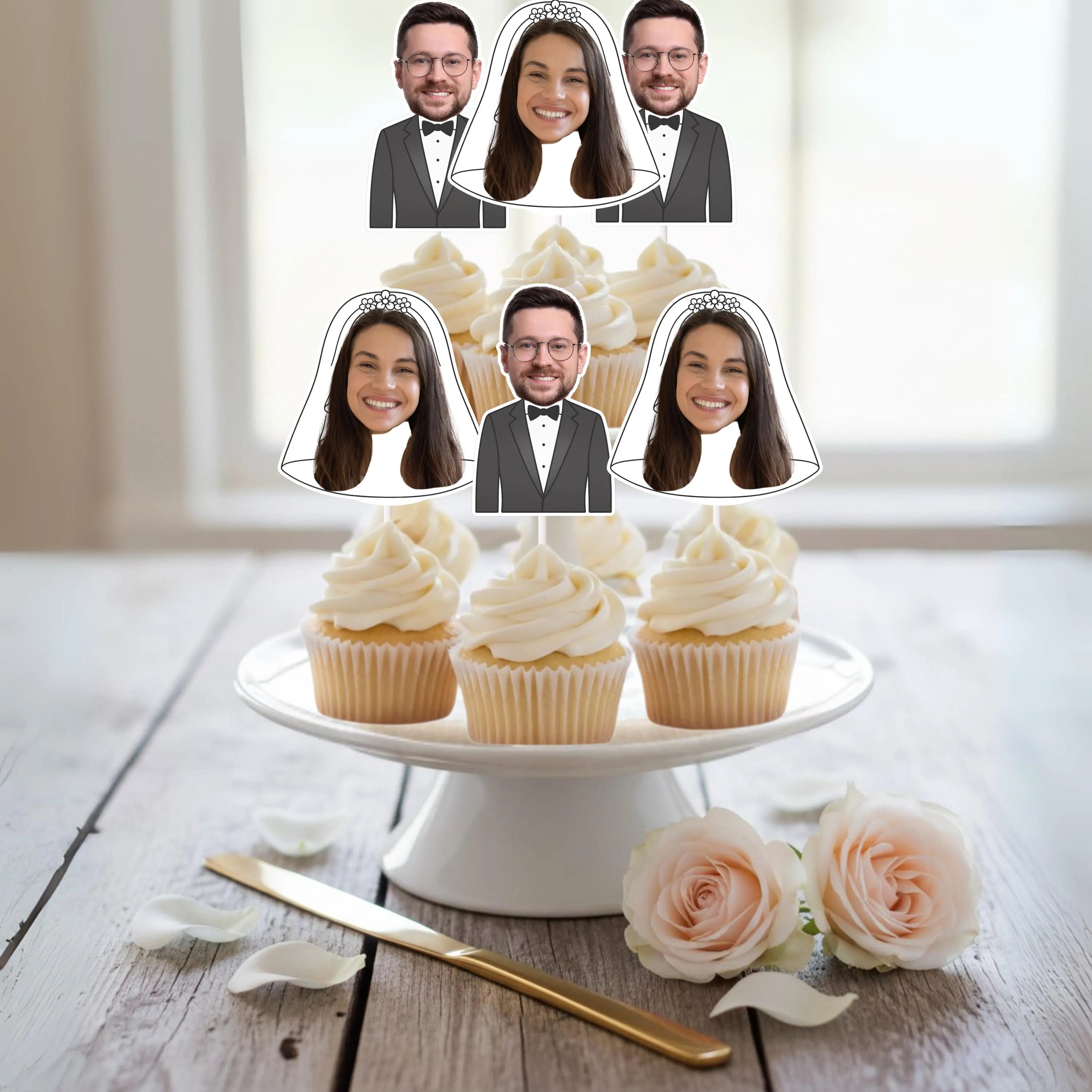 Decorative cake with cupcakes and personalized face cutouts  of Bride and Groom on a wooden table.