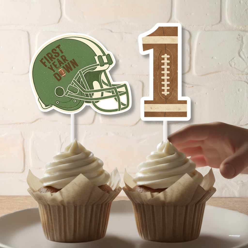 Close up of First Year Down football helmet cupcake topper and textured number one topper placed in vanilla cupcakes. This personalized football first birthday decoration adds a sporty touch to a Rookie of the Year dessert table setup.