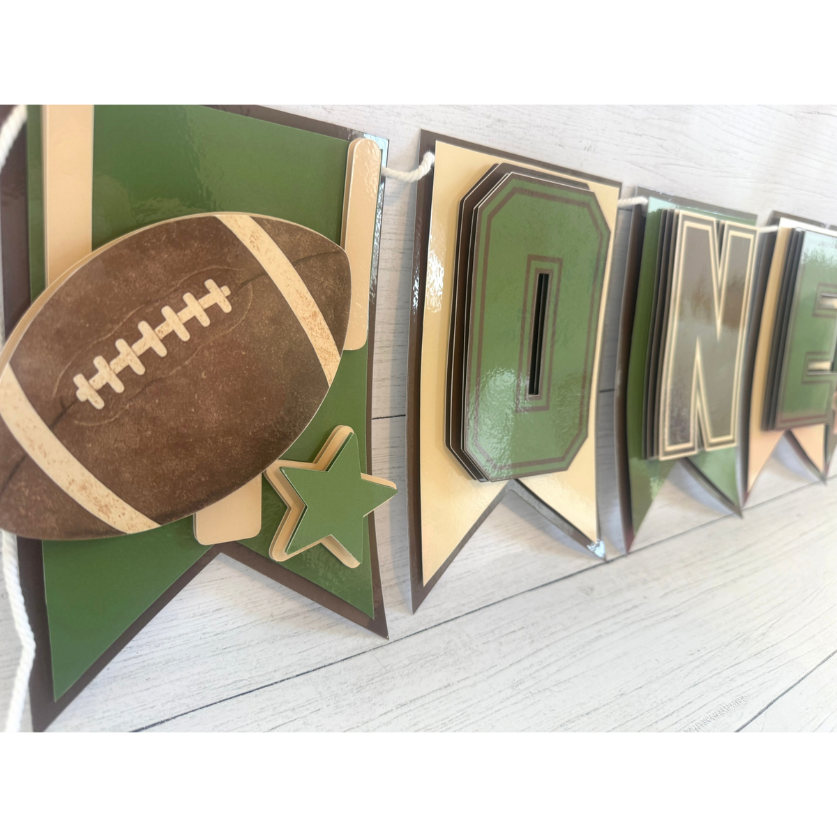 Closeup of layered football and star detail on the First Year Down football highchair banner