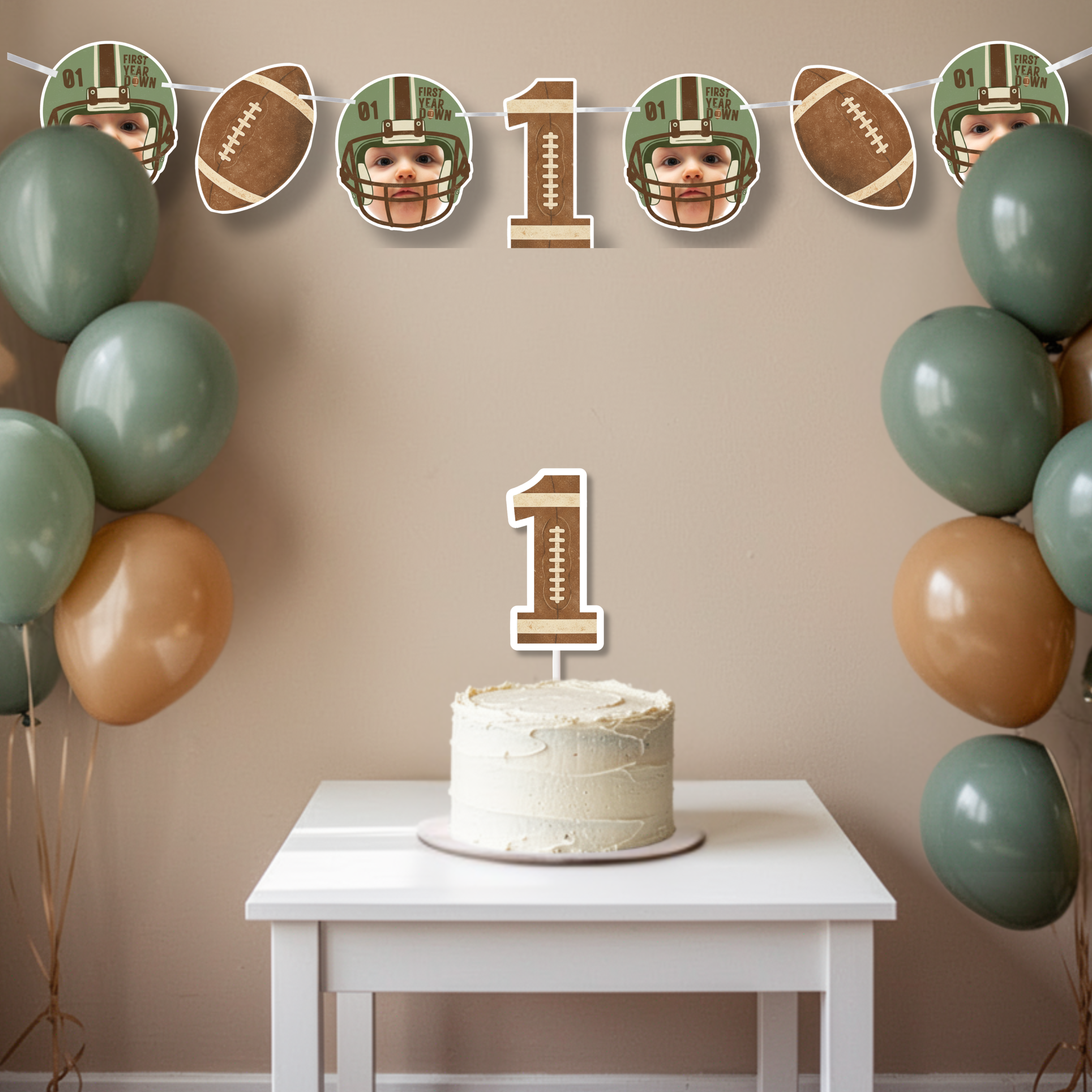 Football themed First Year Down birthday banner hung above a simple smash cake display with neutral balloons and number one cake topper. Sports first birthday party backdrop featuring personalized baby photo helmet graphics.