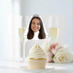 Cupcake with a face cutout on top, set against a blurred background of flowers and candles.