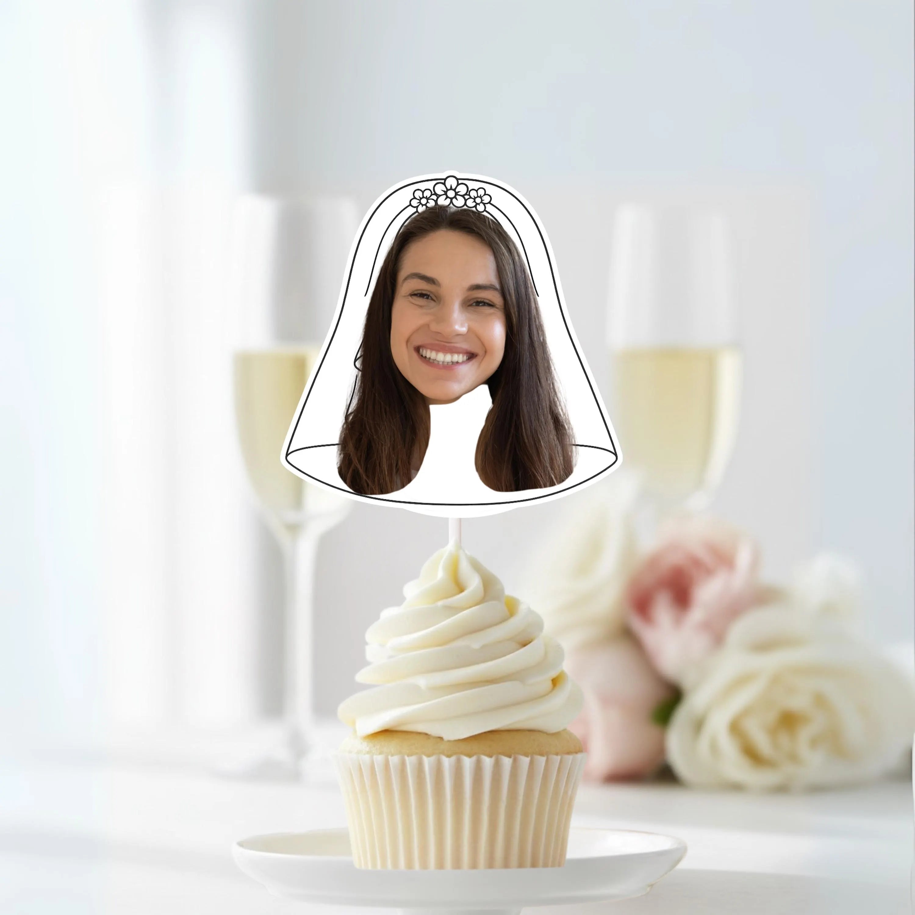 Cupcake with a face cutout on top, set against a blurred background of flowers and candles.