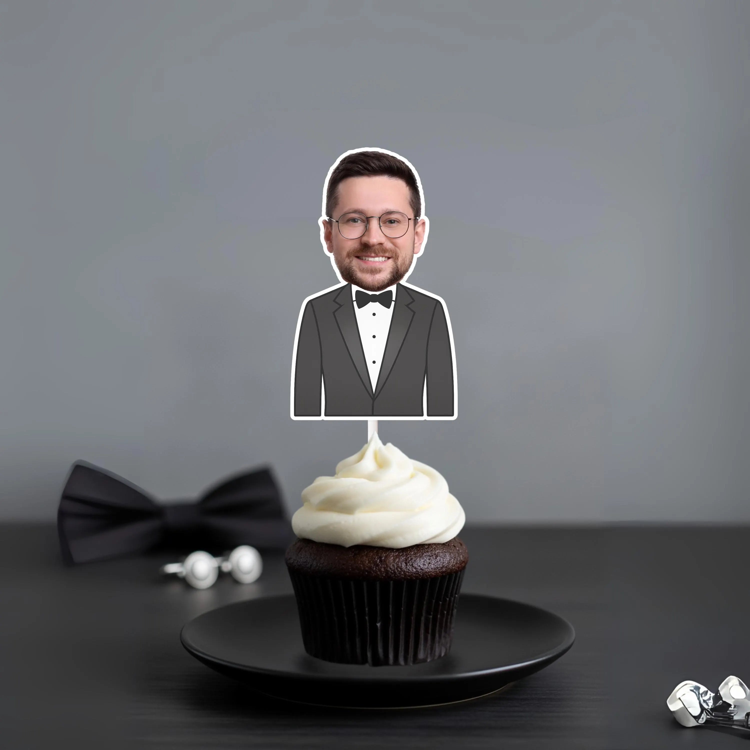Cupcake with a topper of a man in a suit on a dark surface with a gray background