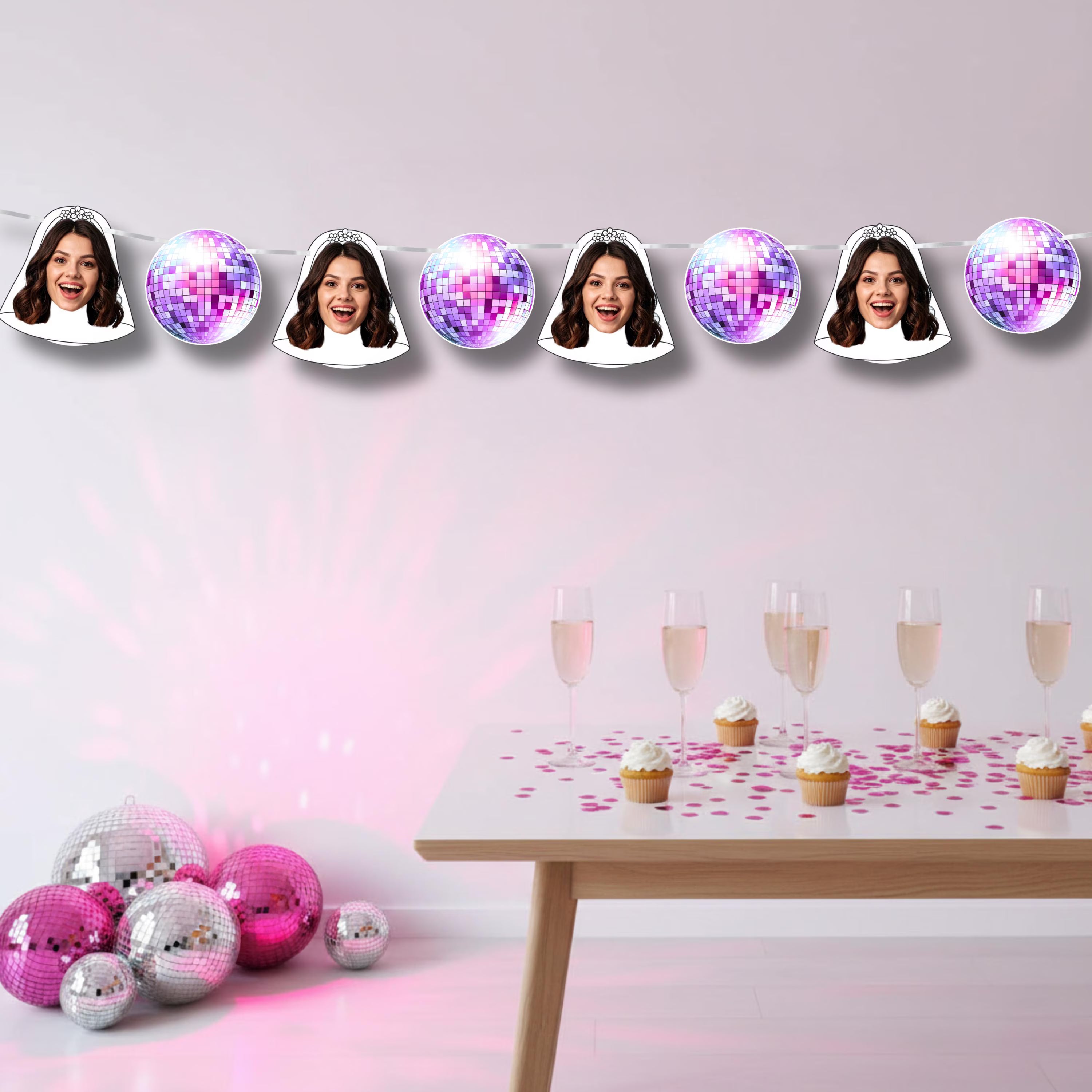 Decorative string with face cutouts and disco balls above a table with drinks and cupcakes.