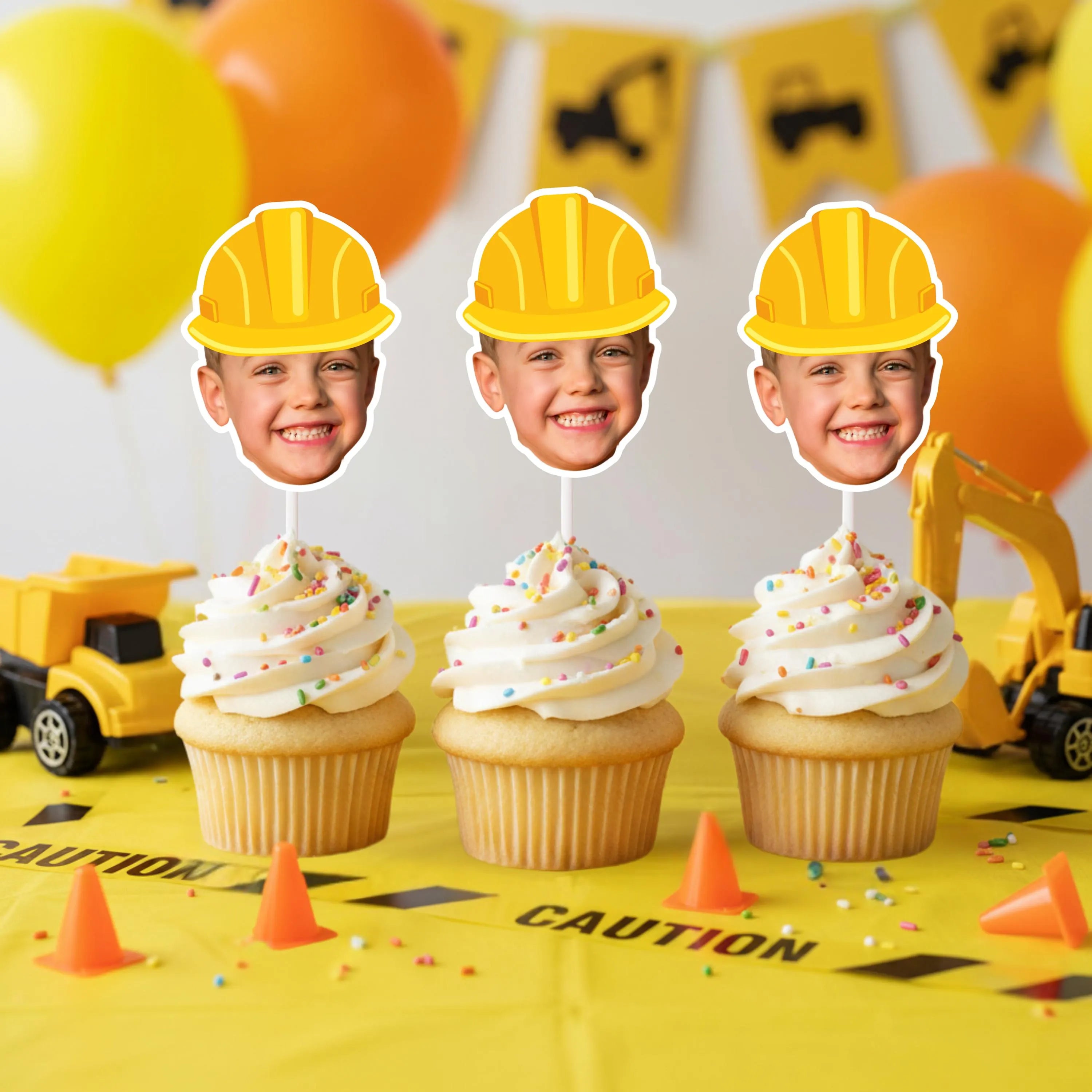 Cupcakes with construction-themed face cards on a yellow tablecloth with construction elements.