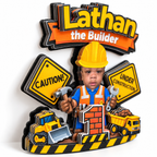Close up angled view of a personalized construction cake topper showing the layered cardstock design with caution signs construction vehicles childs photo and age number