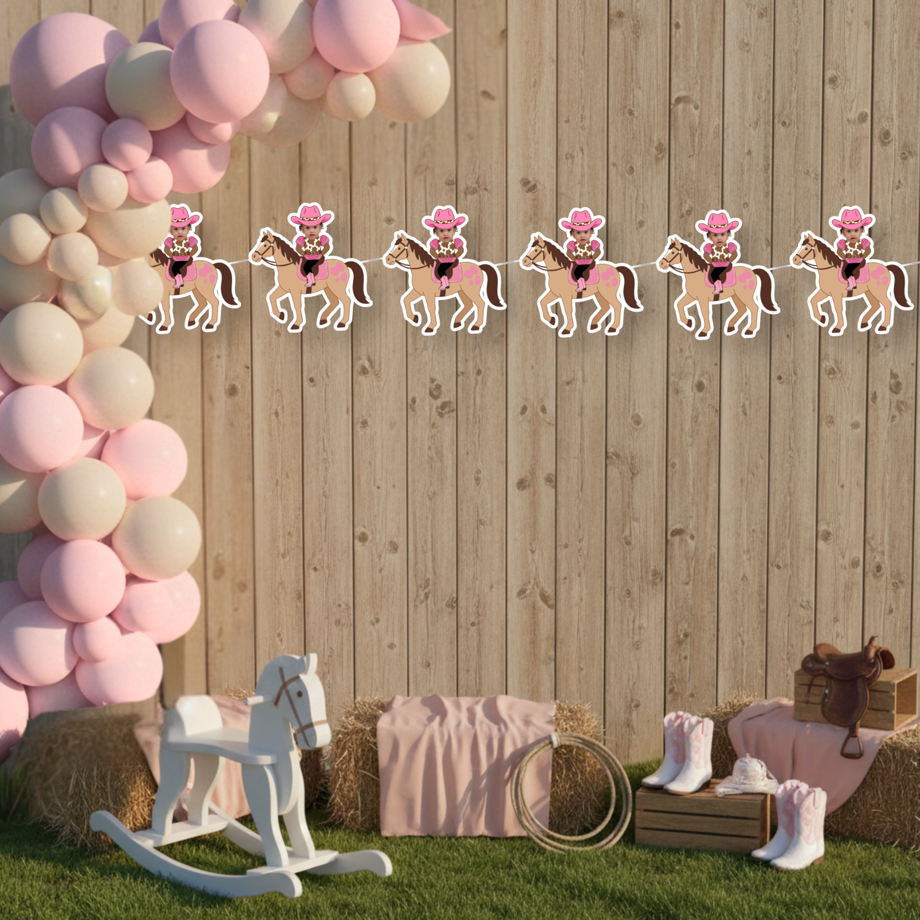 Personalized My First Rodeo cowgirl photo banner displayed on a rustic wood backdrop with pink balloon arch, perfect for a pink western first birthday party. This styled mockup shows the cowgirl photo banner hanging against a barn wood wall with blush balloons, hay bales, and western decor, ideal for cowgirl smash cake and rodeo birthday backdrops.