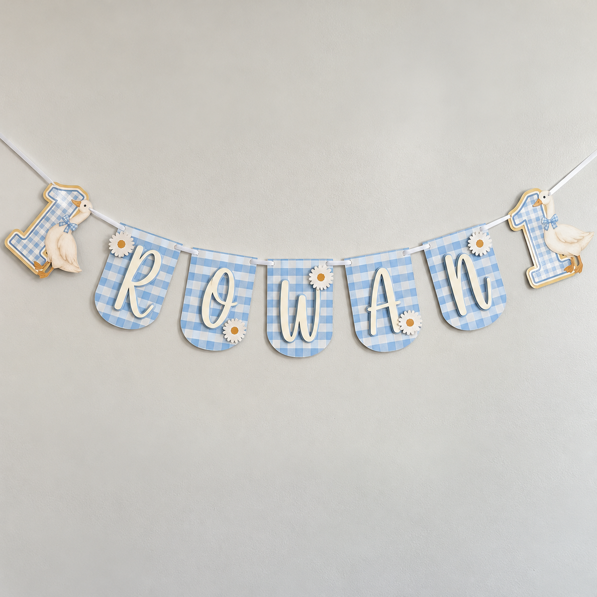Personalized One Silly Goose first birthday banner in blue gingham with the name Rowan, layered daisies, and goose number one end panels.