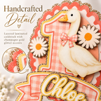 Closeup handcrafted detail of layered laminated One Silly Goose cake topper with pink gingham, daisies and champagne gold glitter cardstock accents
