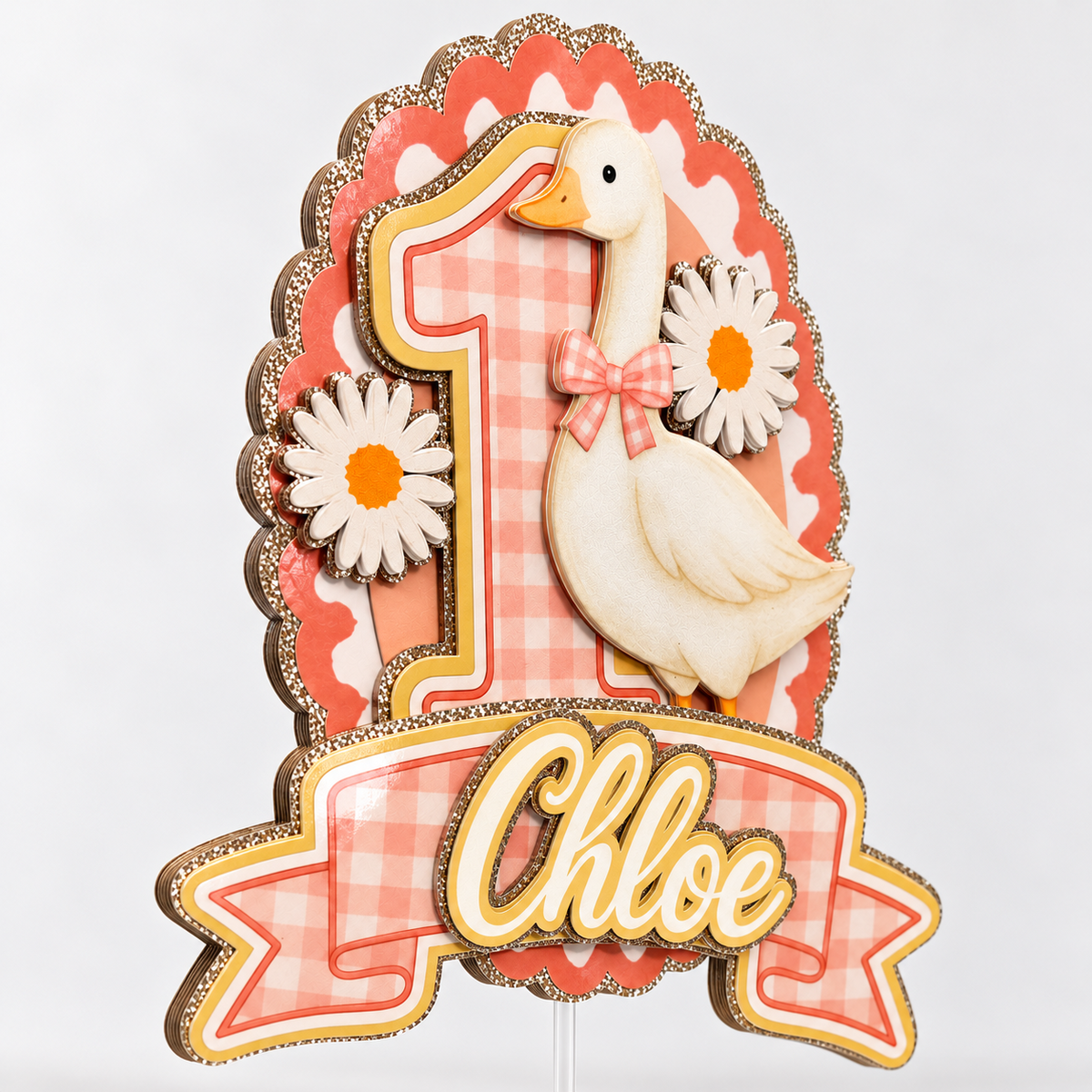 Angled side view of layered One Silly Goose birthday cake topper with laminated cardstock, daisies, pink gingham and champagne gold glitter accents