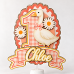 Front view of personalized silly goose birthday cake topper with pink gingham number, white goose, daisies, custom name and champagne gold glitter trim