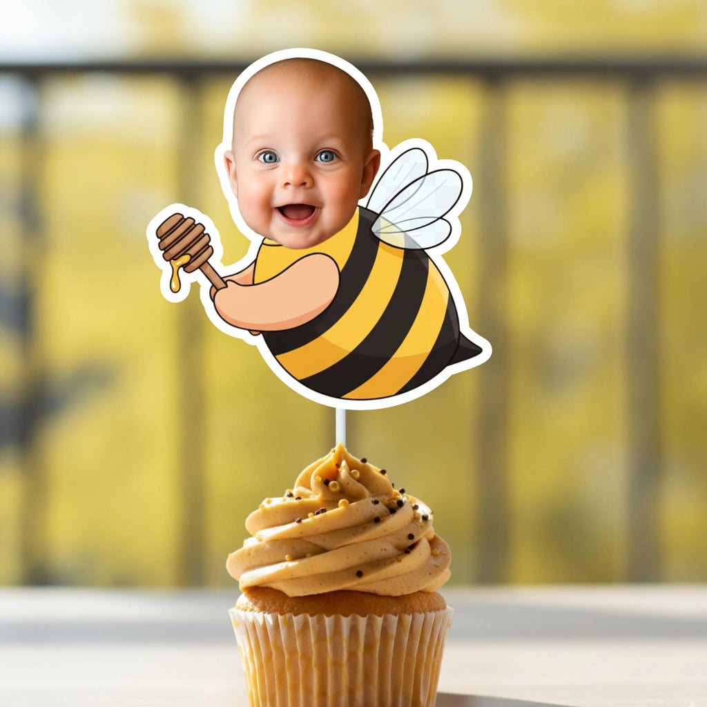 Cupcake with a bee-themed topper featuring a baby face on a blurred yellow background
