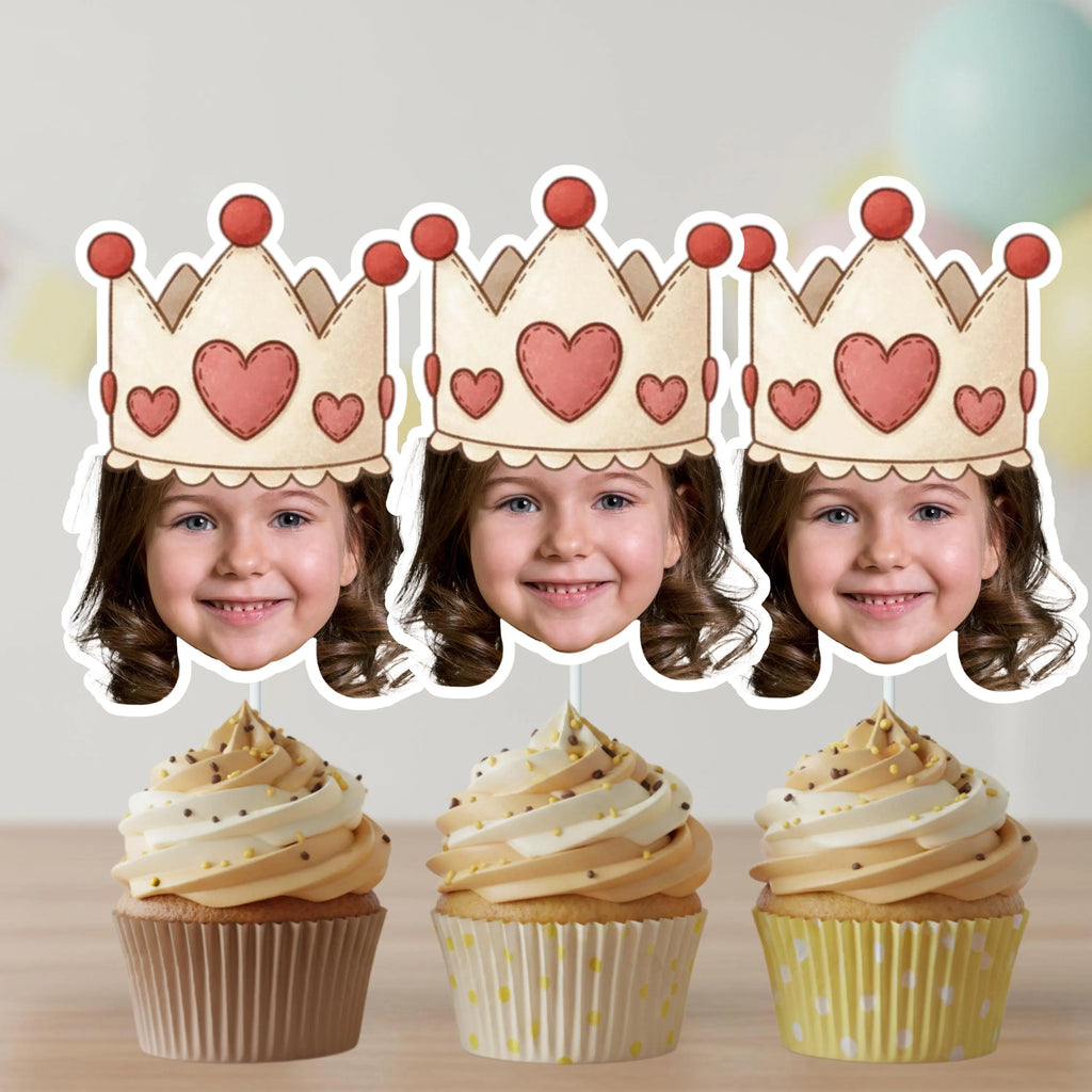 Set of personalized princess face cupcake toppers with heart crown design displayed on three cupcakes with pink frosting and sprinkles. Custom royal birthday party decorations ideal for little princess themes, toddler birthday parties, castle tea parties, and pink and gold dessert table styling.