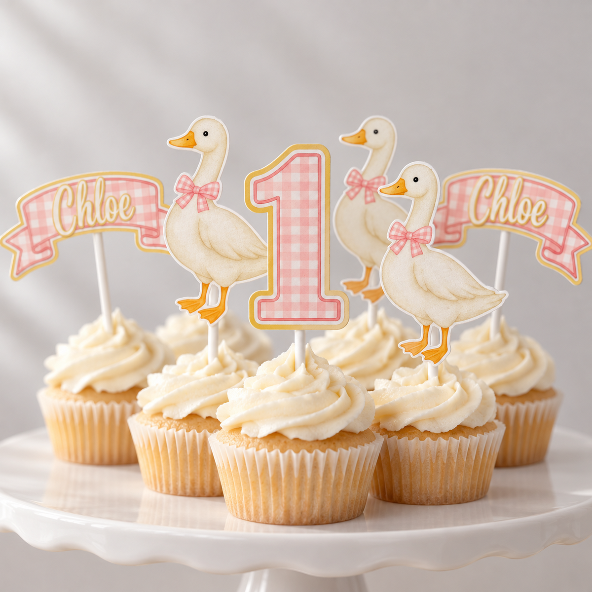 Pink gingham goose first birthday cupcake topper set styled on cupcakes with custom Chloe name banners, number one toppers and matching goose designs.