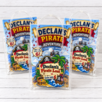Personalized pirate birthday goodie bags shown filled and ready for guests with clear handled favor bags, custom name and age stickers, and coordinating pirate party contents.