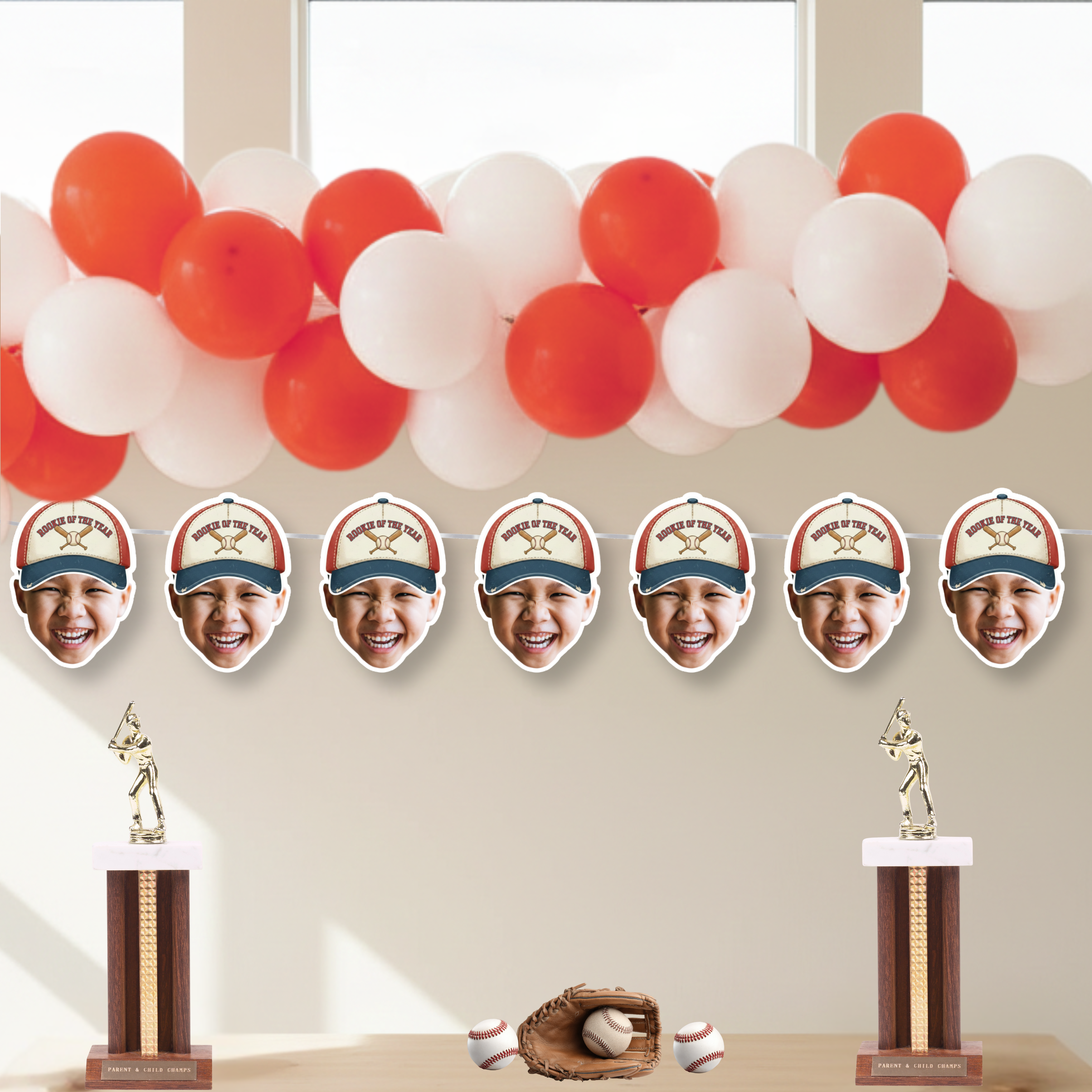 Rookie of the Year photo baseball banner with crossed bats design styled under red and white balloon garland, featuring personalized face cutouts for baseball birthday party decorations and dessert table backdrop.