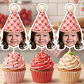 Sweet One custom photo cupcake topper featuring a red and pink heart patterned party hat with white pom pom displayed on a pink and cream swirled cupcake. Personalized first birthday smash cake decoration ideal for love themed baby girl parties and romantic dessert table setups.